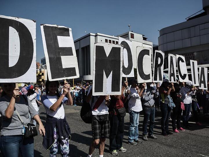 Regierungskritische Demonstranten halten in Caracas Plakate mit dem Schriftzug "Demokratie".