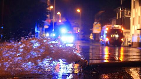 Wasser, das aus einem Keller in Erkrath gepumpt wurde, wird mit einem Feuerwehrschlauch auf die Straße geleitet.