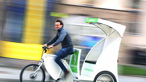 Flott unterwegs: Dominic Staat heizt mit einer seiner strahlend weißen Rikschas durch die Münchner Innenstadt.