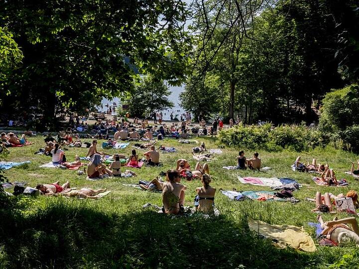 Diese Ausflügler am Ufer des Schlachtensees in Berlin proben schon einmal probate Mittel gegen die kommende Hitze.