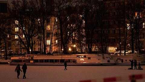Trotz Absperrung trauen sich am Abend einige Menschen auf das Eis auf dem Berliner Landwehrkanal.