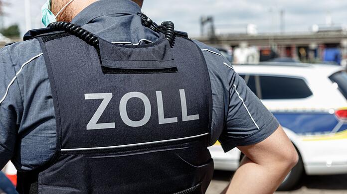 Ein Beamter trägt während seines Dienstes eine Schutzweste mit der Rückenaufschrift "Zoll".