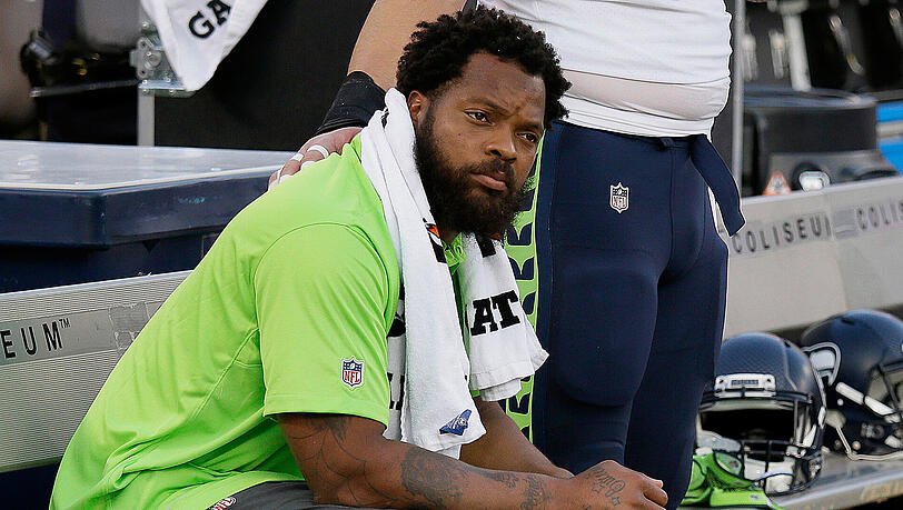 Defensive End Michael Bennett von den Seattle Seahawks sitzt am 31. August vor dem NFL-Preseason-Spiel gegen die Oakland Raiders während der Nationalhymne auf der Bank. Defensive End Michael Bennett von den Seattle Seahawks sitzt am 31. August vor dem NFL-Preseason-Spiel gegen die Oakland Raiders während der Nationalhymne auf der Bank.