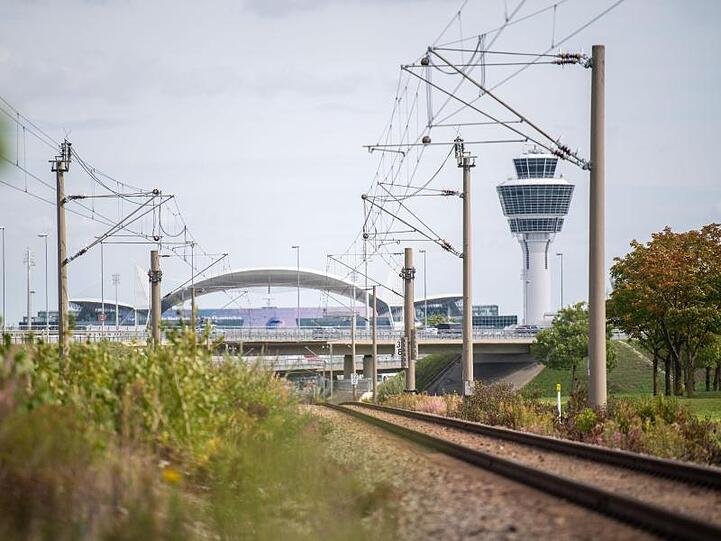 Leere Gleise der S-Bahn führen zum Flughafen München mit dem Tower im Hintergrund. Foto: Lino Mirgeler/dpa
