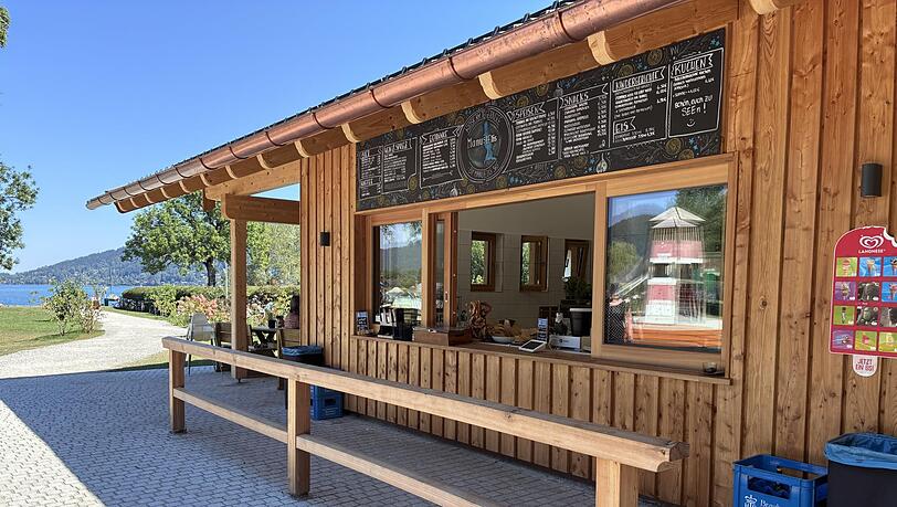 Das moderne Gebäude mit viel hellem Holz in unmittelbarer Nähe zum Tegernsee. Der Kiosk liegt im Rottach-Egener Ortsteil Schorn – direkt neben der großen Badewiese – und ist bei schönem Wetter jeweils von 10 bis 20 Uhr geöffnet. Das moderne Gebäude mit viel hellem Holz in unmittelbarer Nähe zum Tegernsee. Der Kiosk liegt im Rottach-Egener Ortsteil Schorn – direkt neben der großen Badewiese – und ist bei schönem Wetter jeweils von 10 bis 20 Uhr geöffnet.