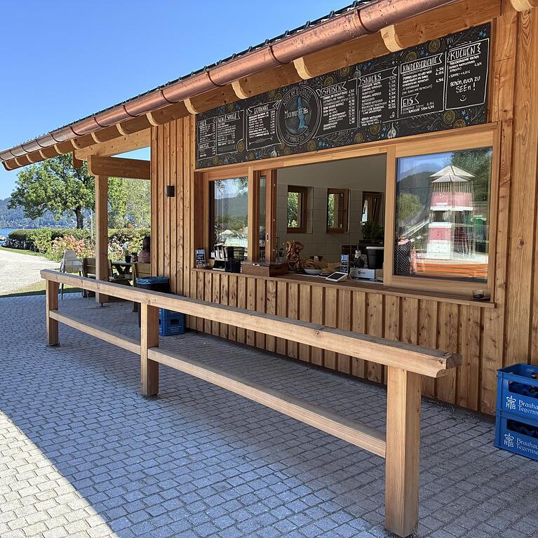 Das moderne Geb&auml;ude mit viel hellem Holz in unmittelbarer N&auml;he zum Tegernsee. Der Kiosk liegt im Rottach-Egener Ortsteil Schorn &ndash; direkt neben der gro&szlig;en Badewiese &ndash; und ist bei sch&ouml;nem Wetter jeweils von 10 bis 20 Uhr ge&ouml;ffnet.