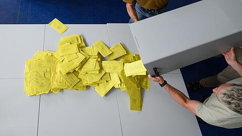 Stimmzettelumschläge für eine Briefwahl werden aus einer Wahlurne geschüttet.