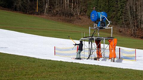 Ein Skifahrer fährt bei schönem Wetter an einem Skihang mit einem Schlepplift.