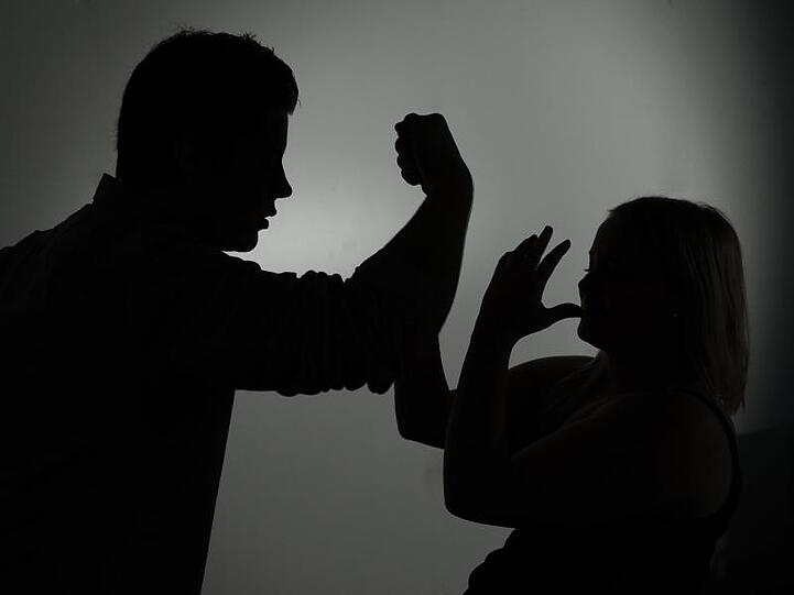 Ein als Silhouette abgebildeter Mann droht einer Frau mit der Faust. Foto: Jan-Philipp Strobel/dpa/Symbolbild