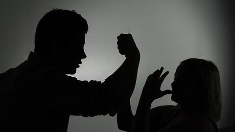 Ein als Silhouette abgebildeter Mann droht einer Frau mit der Faust. Foto: Jan-Philipp Strobel/dpa/Symbolbild