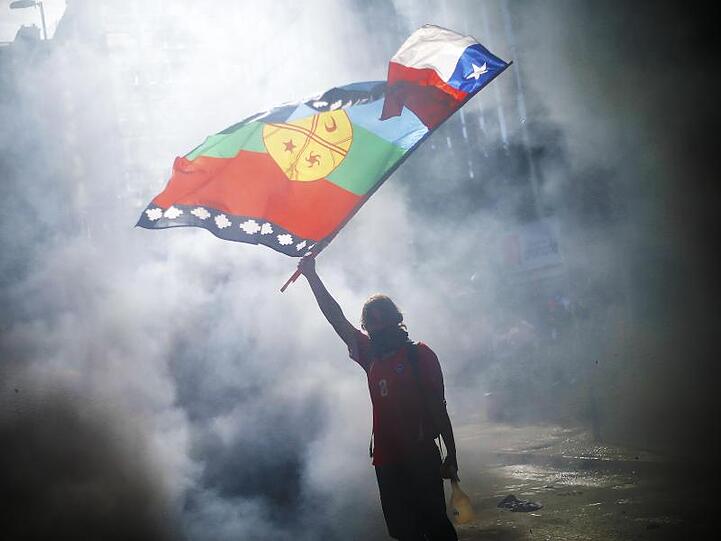 Ein vermummter Demonstrant weht die Flagge von Chile und der indigenen Gemeinschaft Mapuche mitten im Rauch während eines Protestes für Sozialreformen.