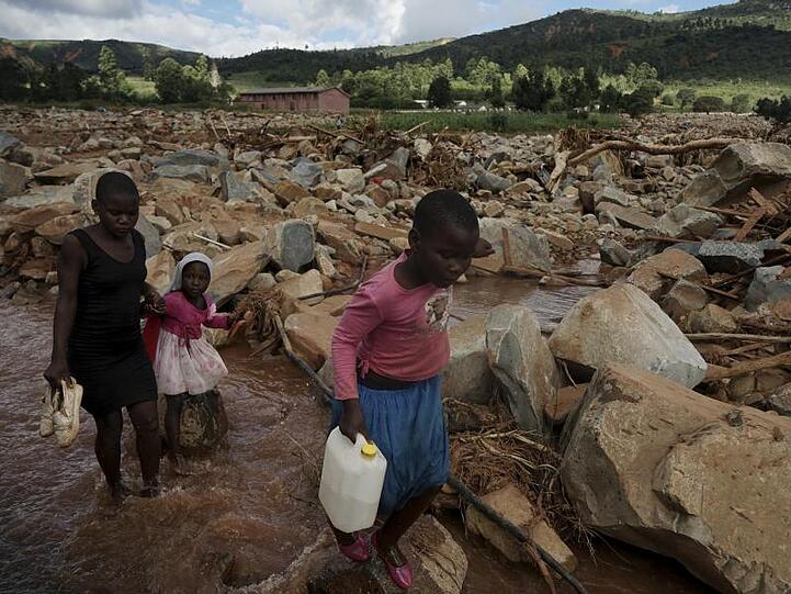 In Chimanimani in Simbabwe überqueren Kinder einen nach Zyklon "Idai" mit Geröll gefüllten Bachlauf.