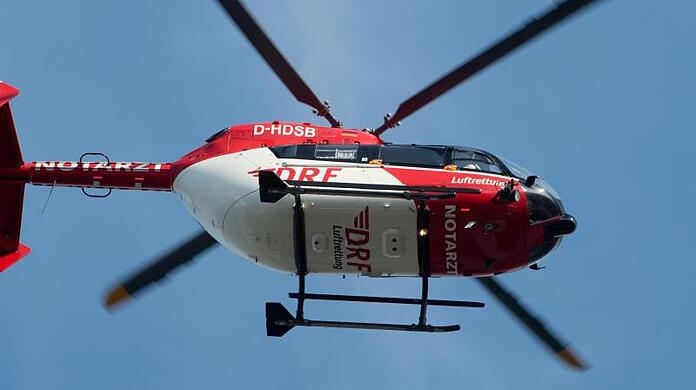 Ein Rettungshubschrauber fliegt über einen Flugplatz.