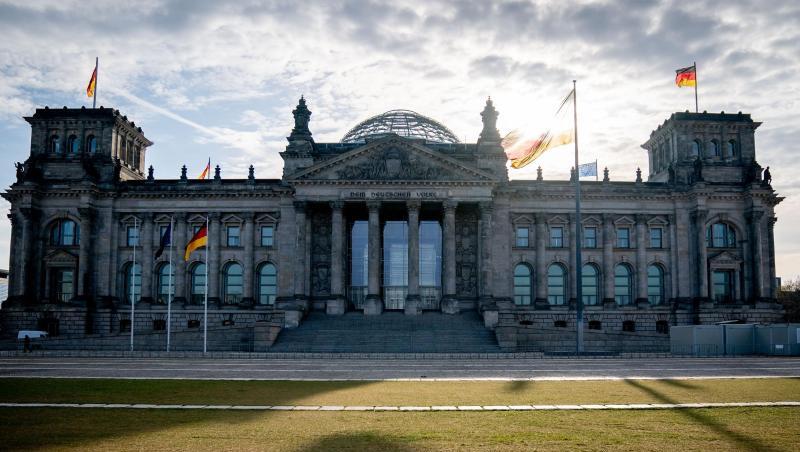 Die Sonne steht am Morgen hinter dem Reichstagsgebäude mit dem Bundestag.