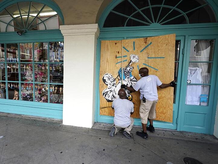 Arbeiter vernageln in Vorbereitung auf Sturm "Marco" die Scheiben eines Geschäfts in New Orleans.