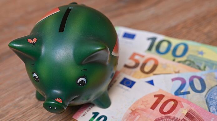 Ein Sparschwein steht auf einem Tisch neben Eurobanknoten.