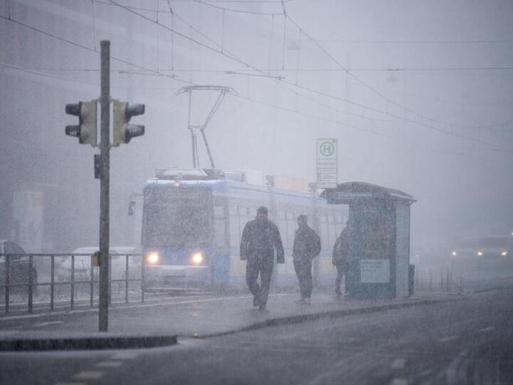 Personen warten an einer Straßenbahnhaltestelle. Foto: Lino Mirgeler/dpa