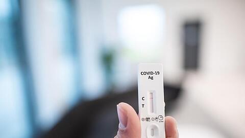 Ein Mann hält einen Corona-Schnelltest in der Hand.