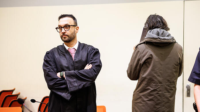 Der angeklagte Mann, der seine Gönnerin aus Habgier getötet haben soll (r), steht vor Prozessbeginn in einem Gerichtssaal vom Landgericht neben seinem Rechtsanwalt Adam Ahmed.