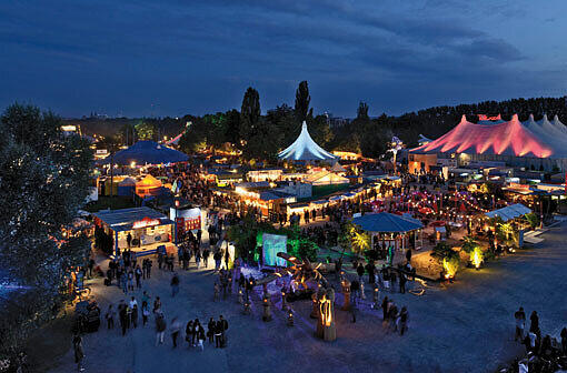 Bald gibt's das wieder am Olympiapark: Das hell erleuchtete Tollwood-Gelände in der Nacht.