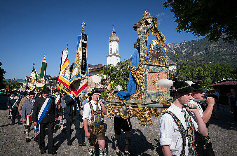 Katholiken ziehen zur Fronleichnamsprozession durch die Gemeinde Garmisch-Partenkichen.