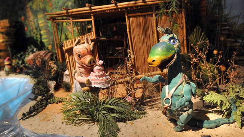 Die Marionette Urmel (r.) bekommt eine Geburtstagstorte von Mama Wutz überreicht.