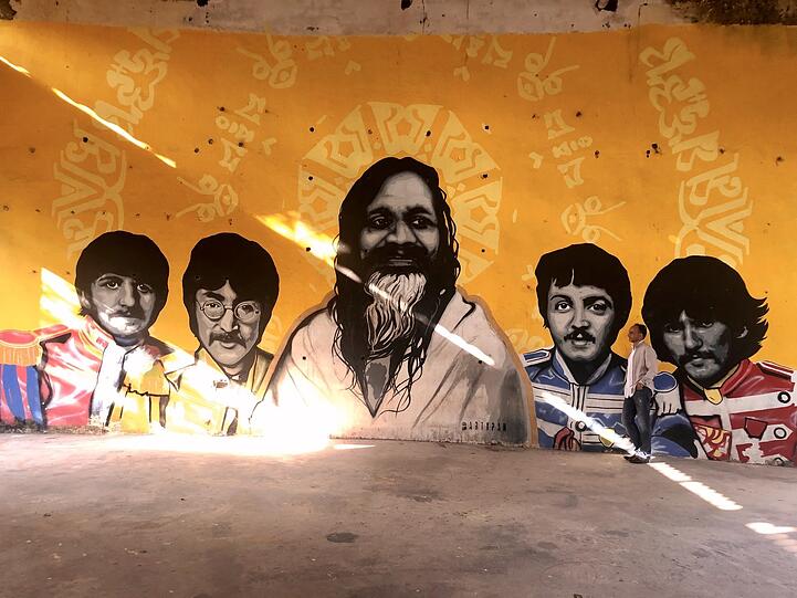Suchbild mit Autor: Daniel Speck im ehemaligen Ashram des Maharishi, in dem auch die Beatles 1968 Zeit verbrachten. Heute sind sie dort auf zahlreichen Graffitis verewigt.