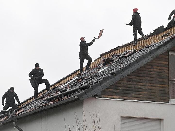 Jetzt beginnt das Reparieren: In einer Kette werfen sich Dachdecker Ziegel zu.