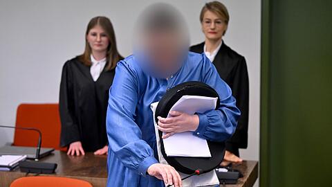 Die Angeklagte Andrea Tandler (M) steht an ihrem Platz im Gerichtssaal zwischen ihren Anwältinnen Cheyenne Blum (l) und Sabine Stetter (r).