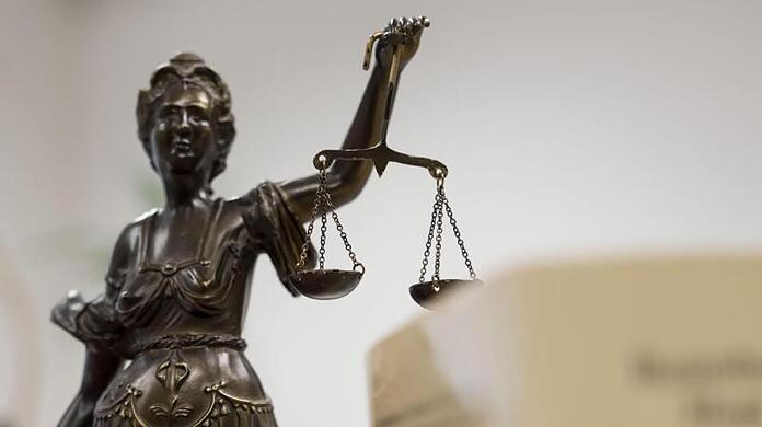 Eine Statue der Justitia hält eine Waage in ihrer Hand.