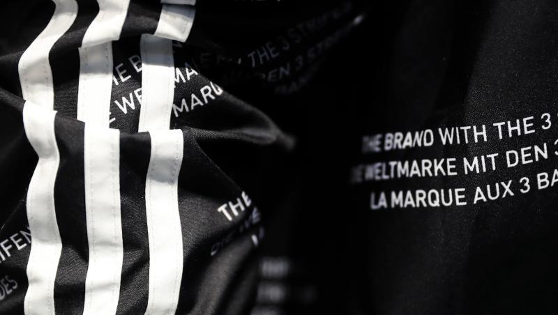 Das Logo des Sportartikelherstellers Adidas und der Schriftzug "Die Marke mit den 3 Streifen". Foto: Daniel Karmann/Archivbild Das Logo des Sportartikelherstellers Adidas und der Schriftzug "Die Marke mit den 3 Streifen". Foto: Daniel Karmann/Archivbild
