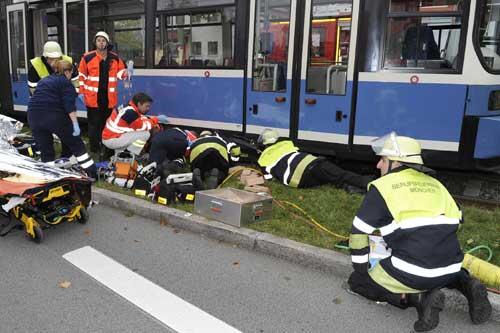 Mit einem Luftkissen heben Feuerwehrleute die Tram, während sich Notärzte um das Opfer kümmern.