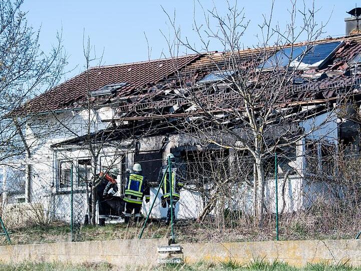 Feuerwehrmänner stehen vor einem ausgebrannten Einfamilienhaus in Bodenkirchen. Foto: Matthias Balk/dpa/Archivbild