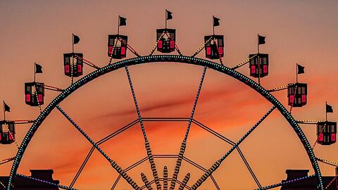 Das Riesenrad auf dem Münchner Königsplatz zeichnet sich vor dem orangefarbenen Himmel ab.