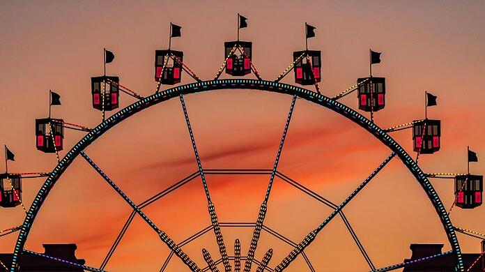 Das Riesenrad auf dem Münchner Königsplatz zeichnet sich vor dem orangefarbenen Himmel ab.