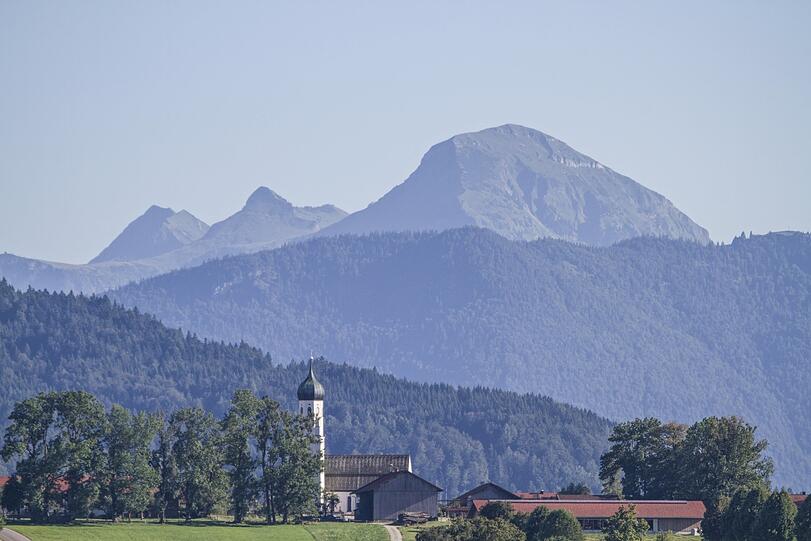 Der Kirchturm von Gaißach bei Tölz im Isartal mit dem gewaltigen Klotz des Juifen im Hintergrund.