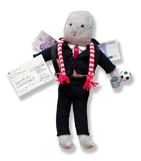 In der Hand hat sie einen Spenden-Scheck über fünf Millionen Euro: "der gute Hoeneß".