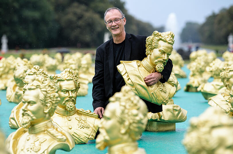 Der N&uuml;rnberger K&uuml;nstler Ottmar H&ouml;rl blickt neben seiner Kunstinstallation zu Ehren des M&auml;rchenk&ouml;nigs K&ouml;nig Ludwig II. im Nymphenburger Schlosspark in die Kamera. 100 Abbilder Ludwigs II. wurden im Rahmen der Kunstinstallation einen Tag vor Ludwigs 173. Geburtstag aufgestellt.