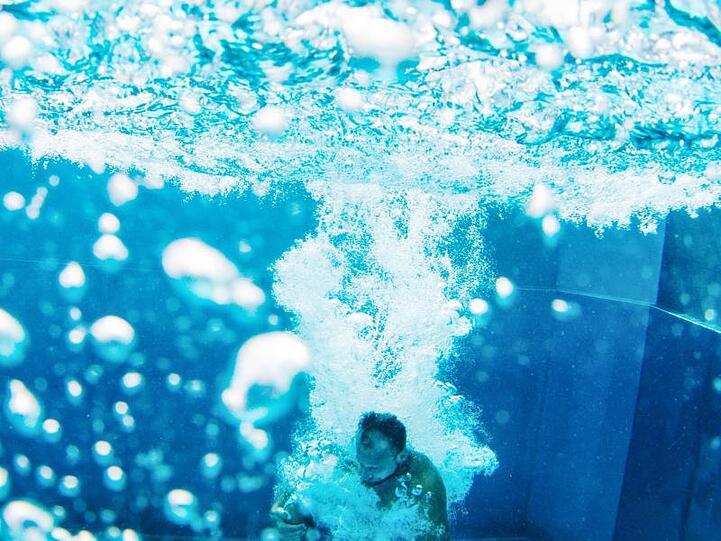 Ein Badegast springt in ein Schwimmbecken. Foto: Jana Bauch/dpa/Archivbild