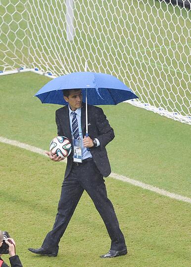 Der Unparteiische Ravschan Irmatov (Usbeskistan) inspiziert mit Regenschirm den Rasen in in Recife.