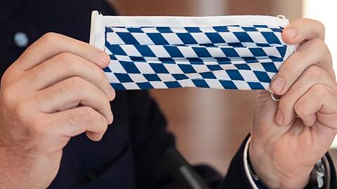 Ministerpräsident Markus Söder (CSU) hält einen Mundschutz mit der bayerischen Flagge in den Händen. Foto: Sven Hoppe/dpa/Archivbild