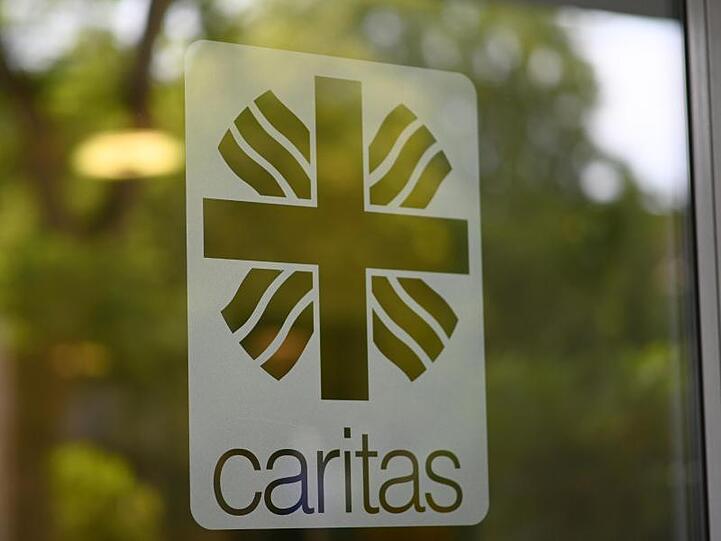 Das Logo der Caritas ist auf einer Glastür angebracht. Foto: Patrick Seeger/Archivbild