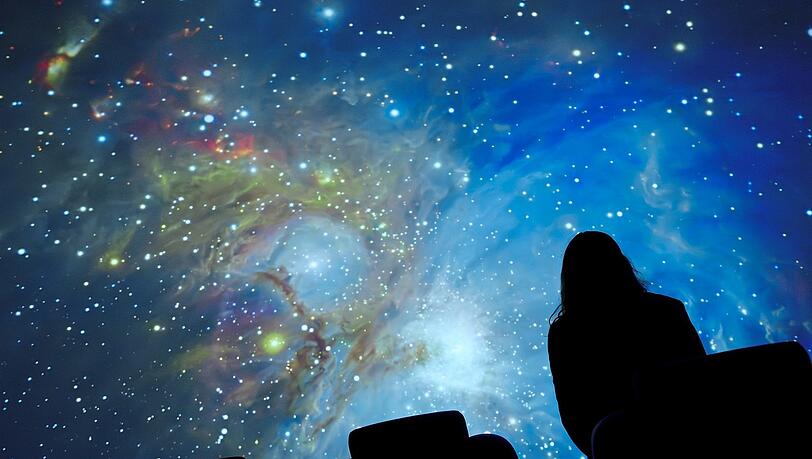 Eine Frau schaut sich im Planetarium der Europäischen Südsternwarte (ESO) den Sternenhimmel an.