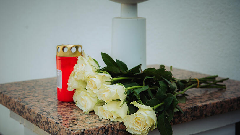 Sieben weiße Rosen liegen neben einer Kerze auf dem Tor-Pfosten der Kessler-Zwillinge Sieben weiße Rosen liegen neben einer Kerze auf dem Tor-Pfosten der Kessler-Zwillinge