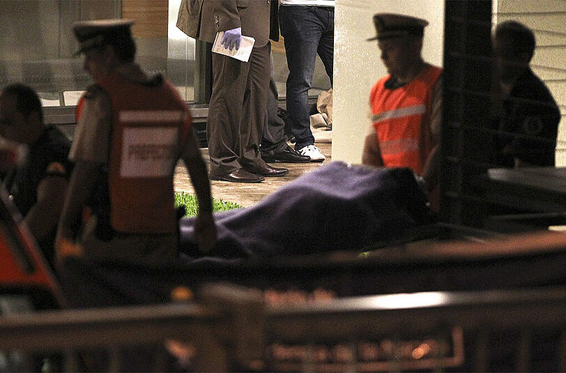 Sicherheitskräfte tragen den Leichnam des Staatsanwalts aus seiner Wohnung. Dort wurde auch eine Waffe gefunden, ob diese jedoch die Tatwaffe ist, ist bisher noch nicht bekannt.