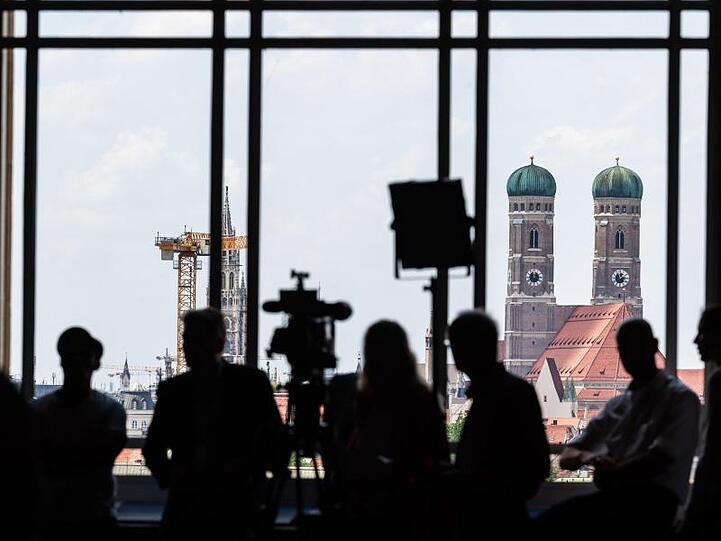 Journalisten warten während der Sitzung des bayerischen Landtags am Fenster vor der Kulisse Münchens. Foto: Peter Kneffel/Archivbild