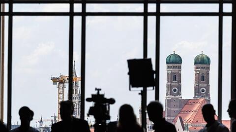 Journalisten warten während der Sitzung des bayerischen Landtags am Fenster vor der Kulisse Münchens. Foto: Peter Kneffel/Archivbild