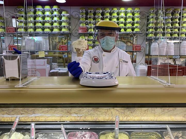 Paolo Costantini serviert mit Schutzausrüstung in seiner römischen Eisdiele &bdquo;Il Gelatone&ldquo; Eis.