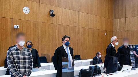 Die zwei wegen Mordes angeklagten Männer (l und 2.v.r.) stehen vor Beginn der Verhandlung mit ihren Anwälten im Sitzungssaal.
