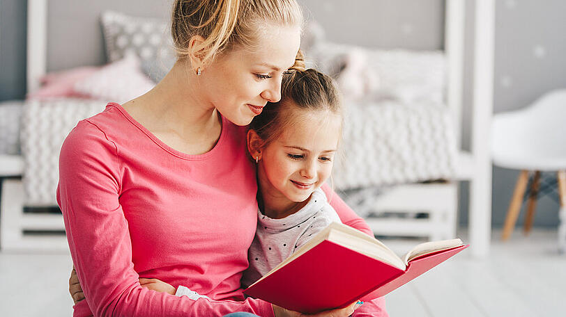 Eine Mutter bringt ihrer Tochter das Lesen bei